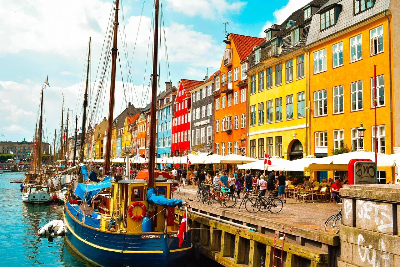 Canal de Nyhavn en Copenhague, Dinamarca, con barcos de vela y casas de colores vibrantes. Un lugar ideal que ver en Dinamarca.