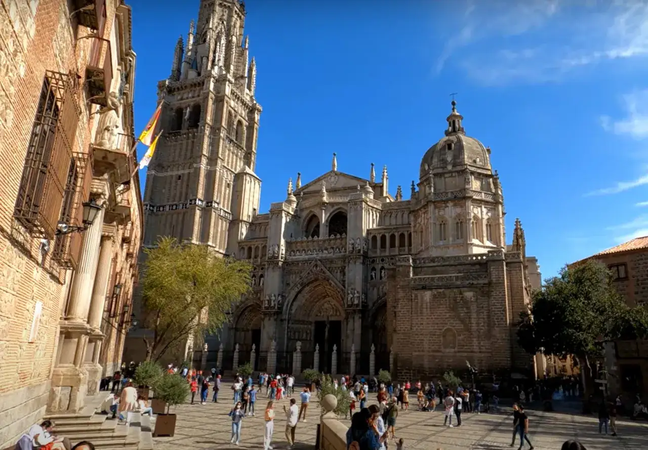 Plaza ante la Catedral de Toledo, ideal para un free tour Toledo. Gente paseando bajo el sol.