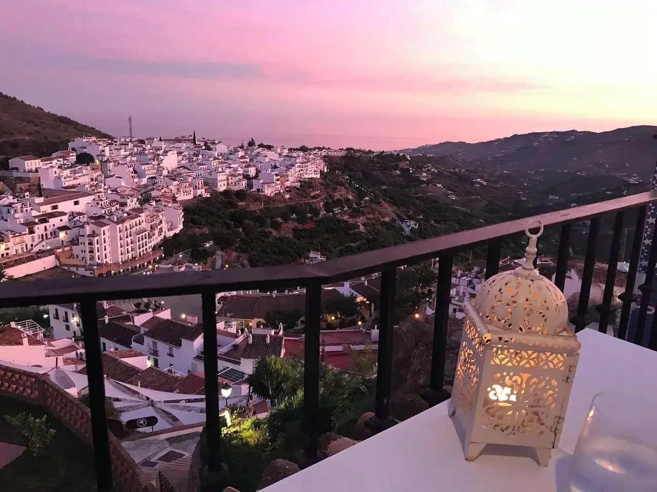 Atardecer rosado sobre Frigiliana. Una linterna ilumina la mesa, perfecta para decidir d&oacute;nde comer en Frigiliana.