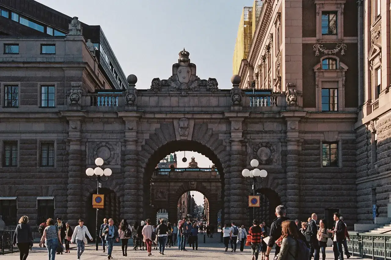 Gente pasea bajo un arco monumental, un lugar que ver en Estocolmo.
