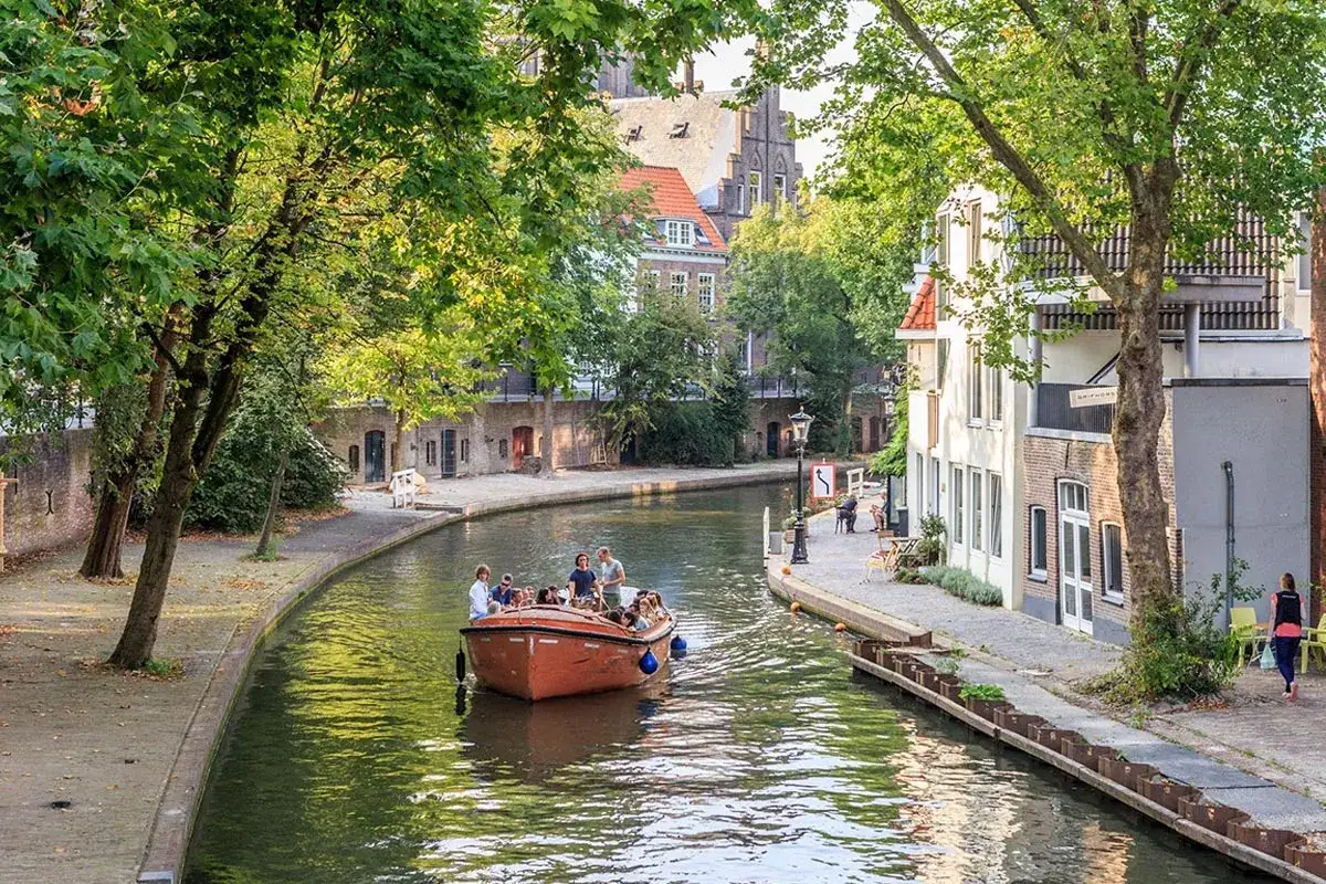 Un paseo en barco por los canales es una excelente idea de qué ver en Holanda. Gente disfrutando del sol y la arquitectura.