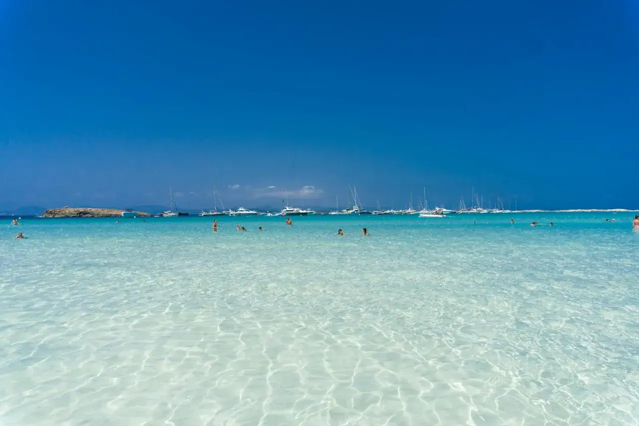 Aguas cristalinas y barcos anclados en un día soleado, un paraíso que confirma las mejores playas de Formentera.