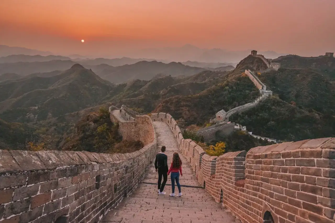 Pareja camina por la Gran Muralla China al atardecer. El otoño es la mejor época para viajar a China, con cielos despejados y paisajes espectaculares.