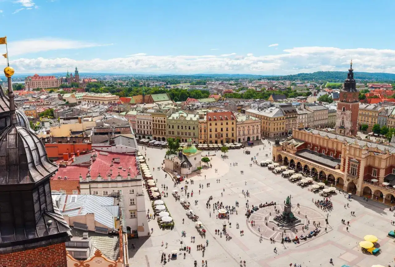 Vista aérea de la Plaza del Mercado de Cracovia, ideal para saber qué ver en Cracovia en 3 días. Edificios históricos, gente y el Castillo de Wawel al fondo.