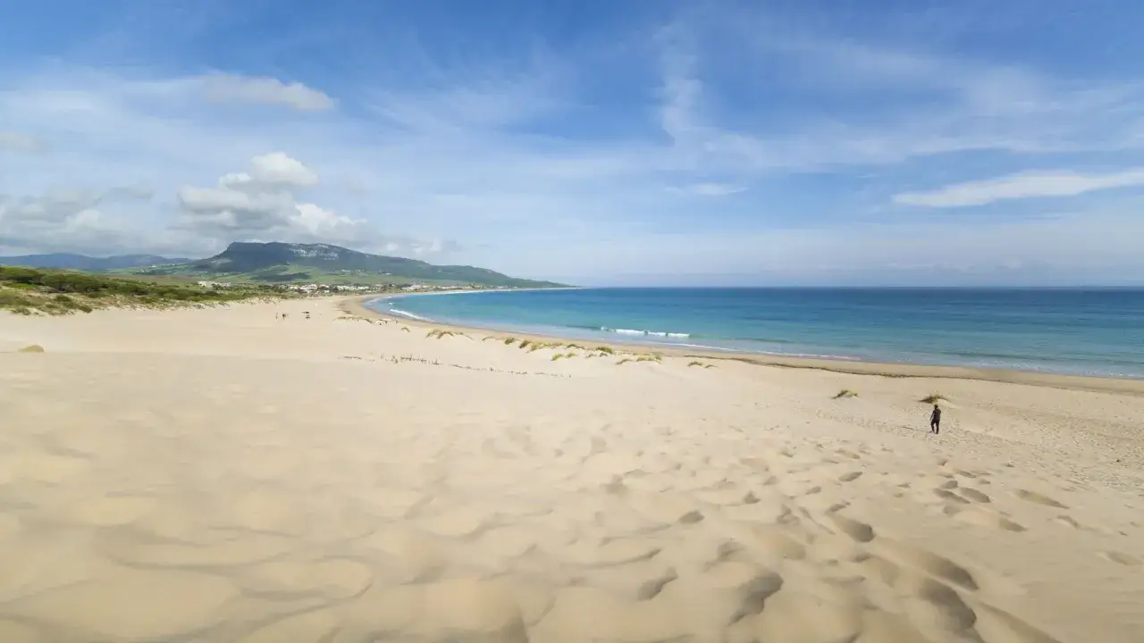 Extensa playa de dunas doradas y arena fina, con el mar azul turquesa al fondo. Un paraíso entre las mejores playas de Andalucía.