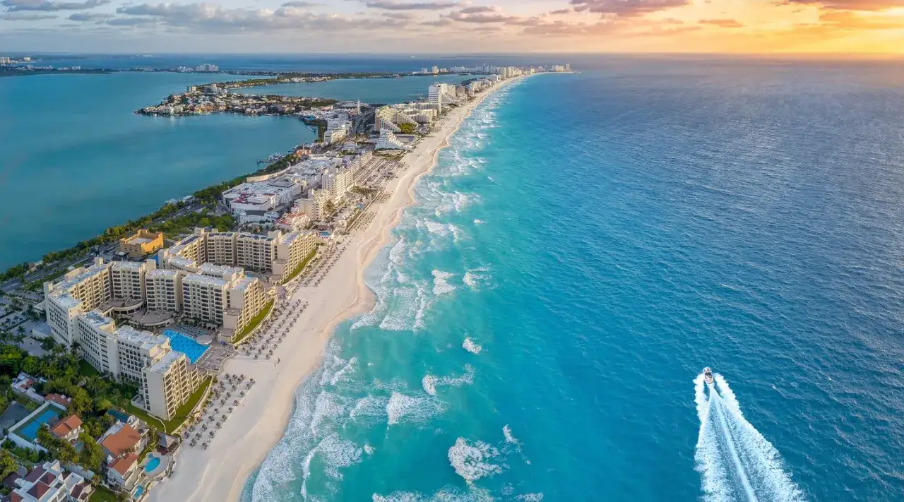 Vista aérea de Cancún, México. Hoteles, playa de arena blanca y mar turquesa invitan a viajar a México. Una lancha surca las olas.