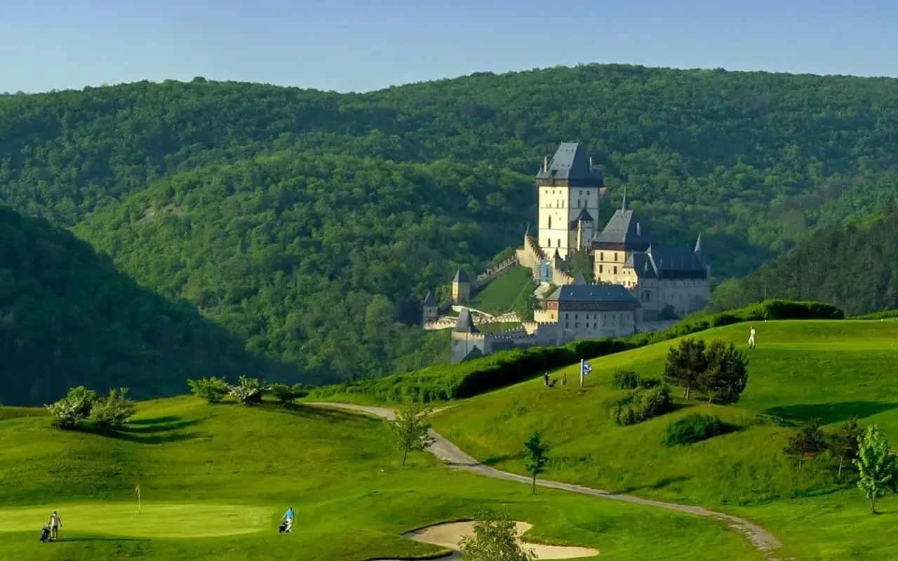 Castillo Karlštejn, ideal para excursiones en Prague, rodeado de colinas verdes y un campo de golf.