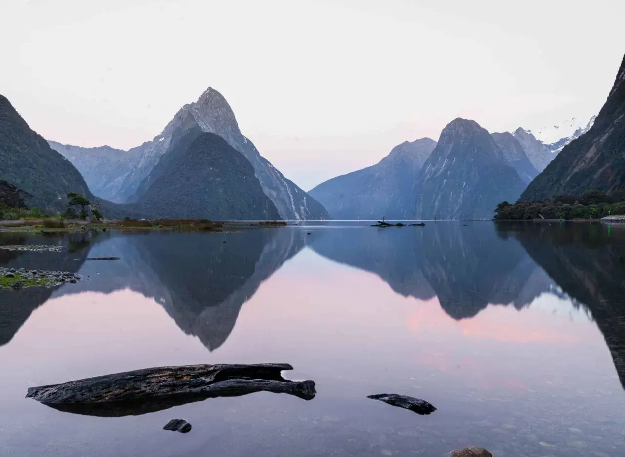 Impresionante reflejo de montañas en un lago sereno, un paisaje imperdible de Nueva Zelanda que ver.