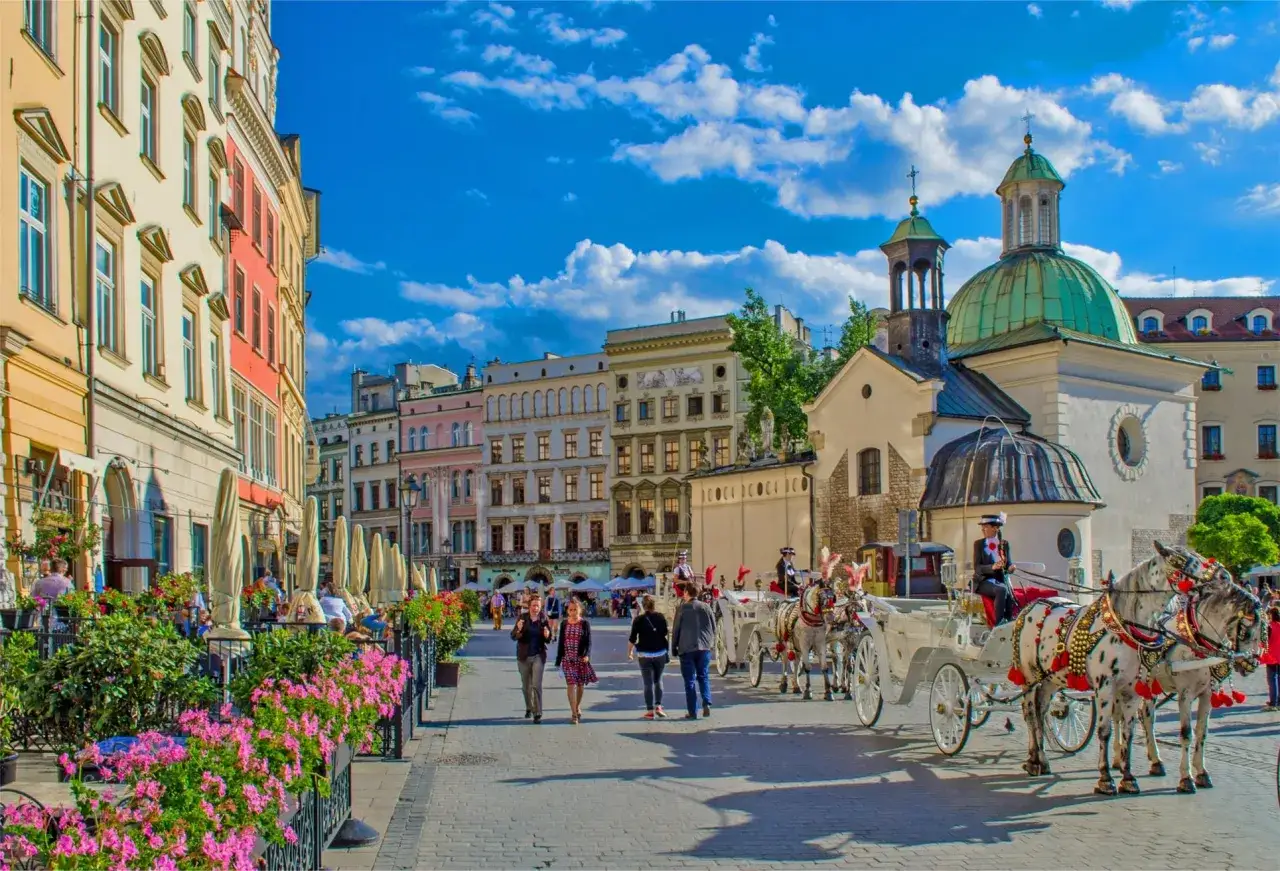Un paseo en carruaje por Cracovia, con edificios históricos, flores y gente disfrutando del día.